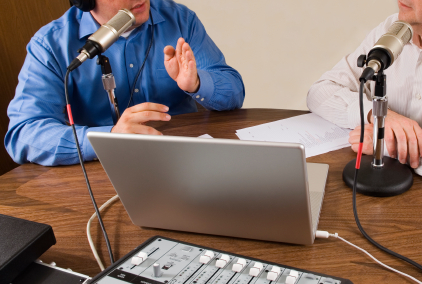 one man speaking into a microphone with computer in front of him